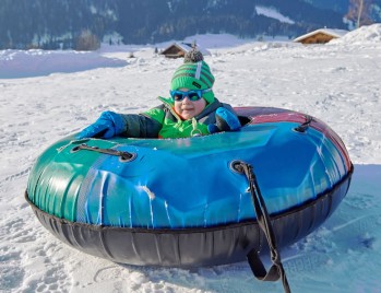 Kind in einem Tubingreifen an einem schönen Wintertag in Sankt Martin am Tennengebirge